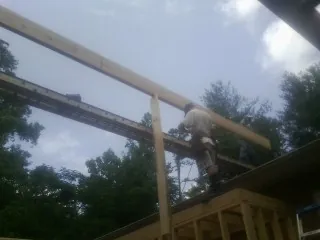 Carpenter setting a ridge beam over a new addition frame — Ice Dam Removal by Roofing Brothers in Carney