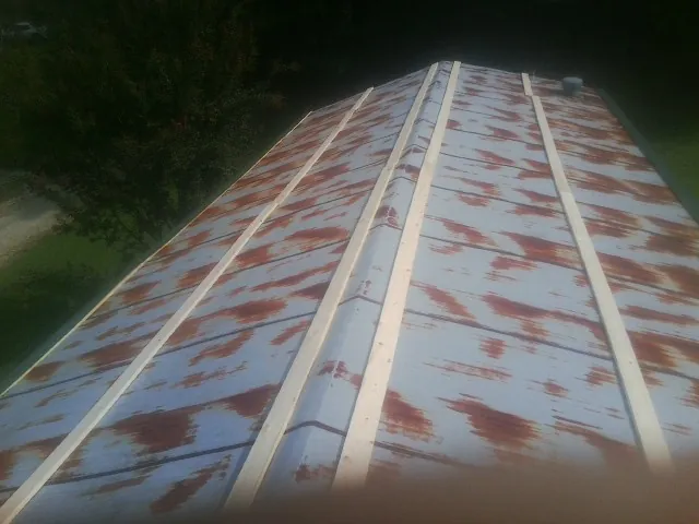 Rusted metal roof panels with new wood purlins before replacement — Storm Damage Roof Repair in Carney by Roofing Brothers