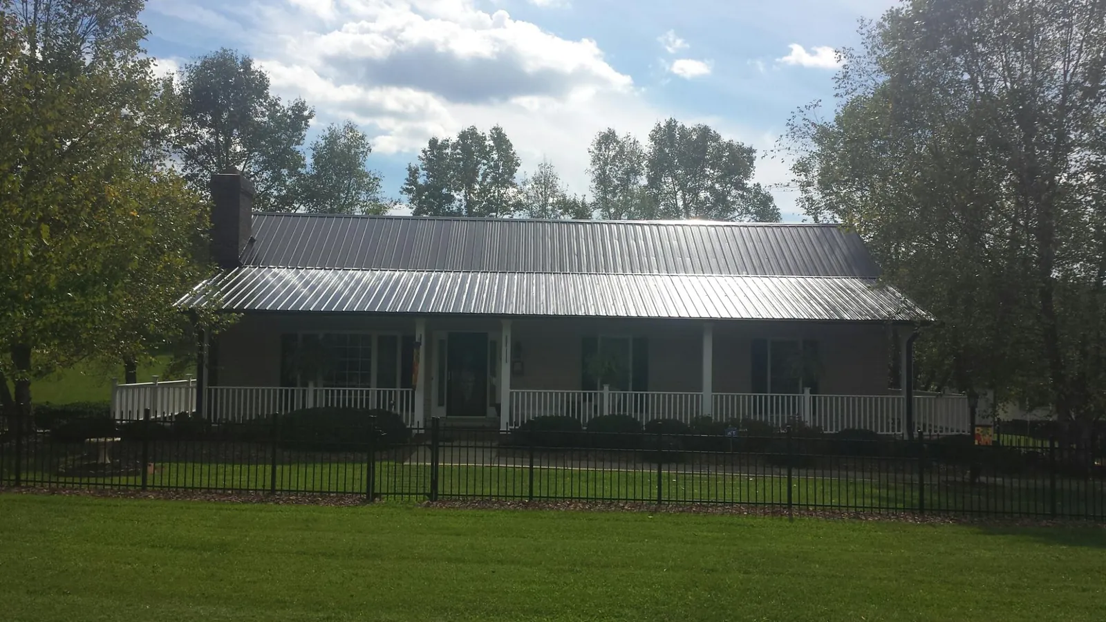 Gray metal roof on a brick ranch with a full width front porch — Gutter Guard Installation work by our crew in Carney