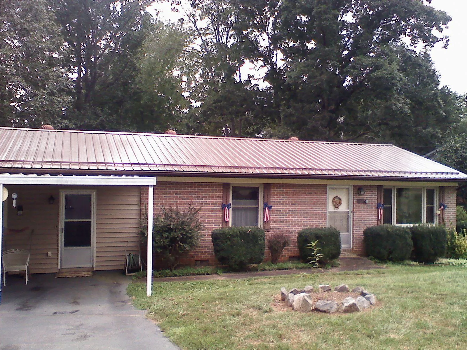 Bronze metal roof and carport on a brick ranch home — Roof Repair work by our crew in Carney