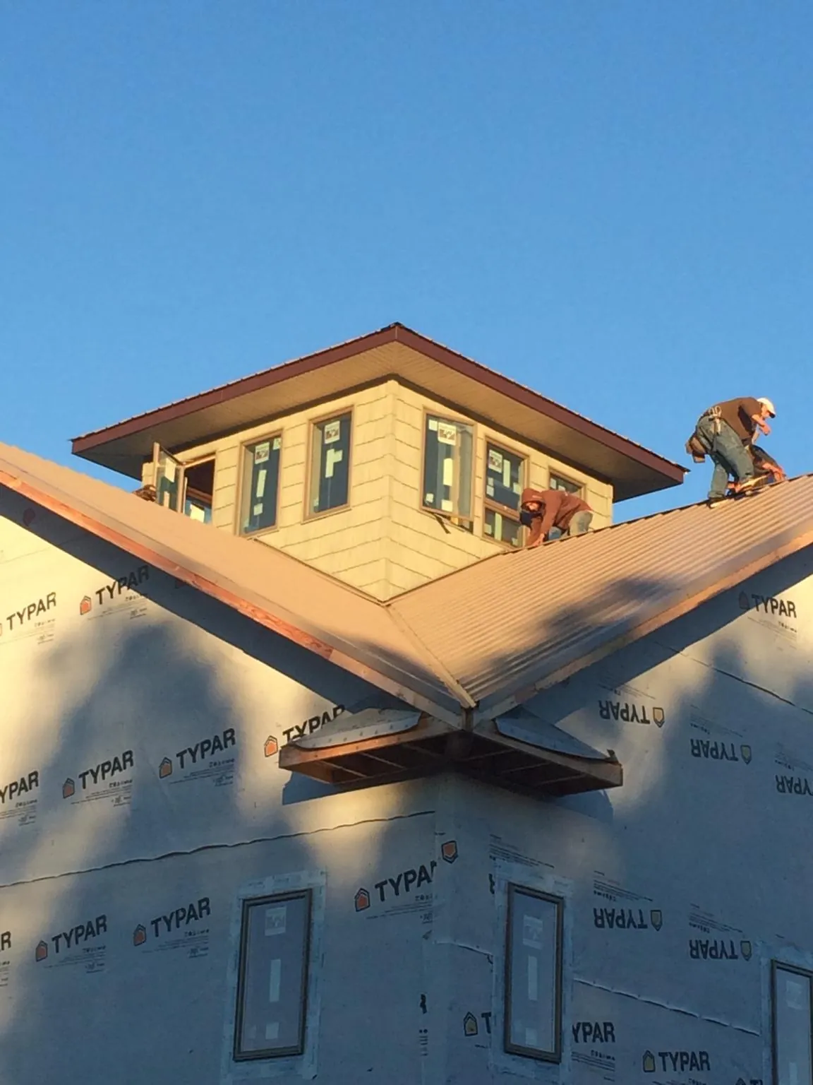 Roofers working around a rooftop cupola on a new metal roof at sunset — Roof Waterproofing in Carney by Roofing Brothers
